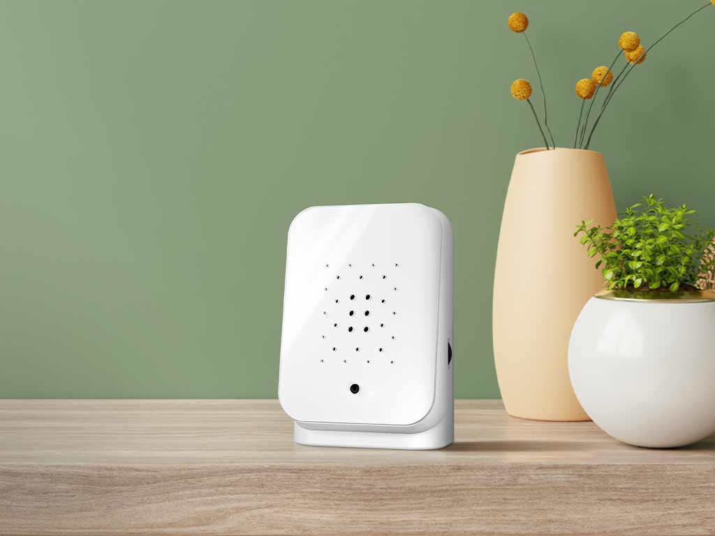 Witte Junglebox op een houten tafel naast een plant in een witte pot en een gele vaas tegen een groene muur