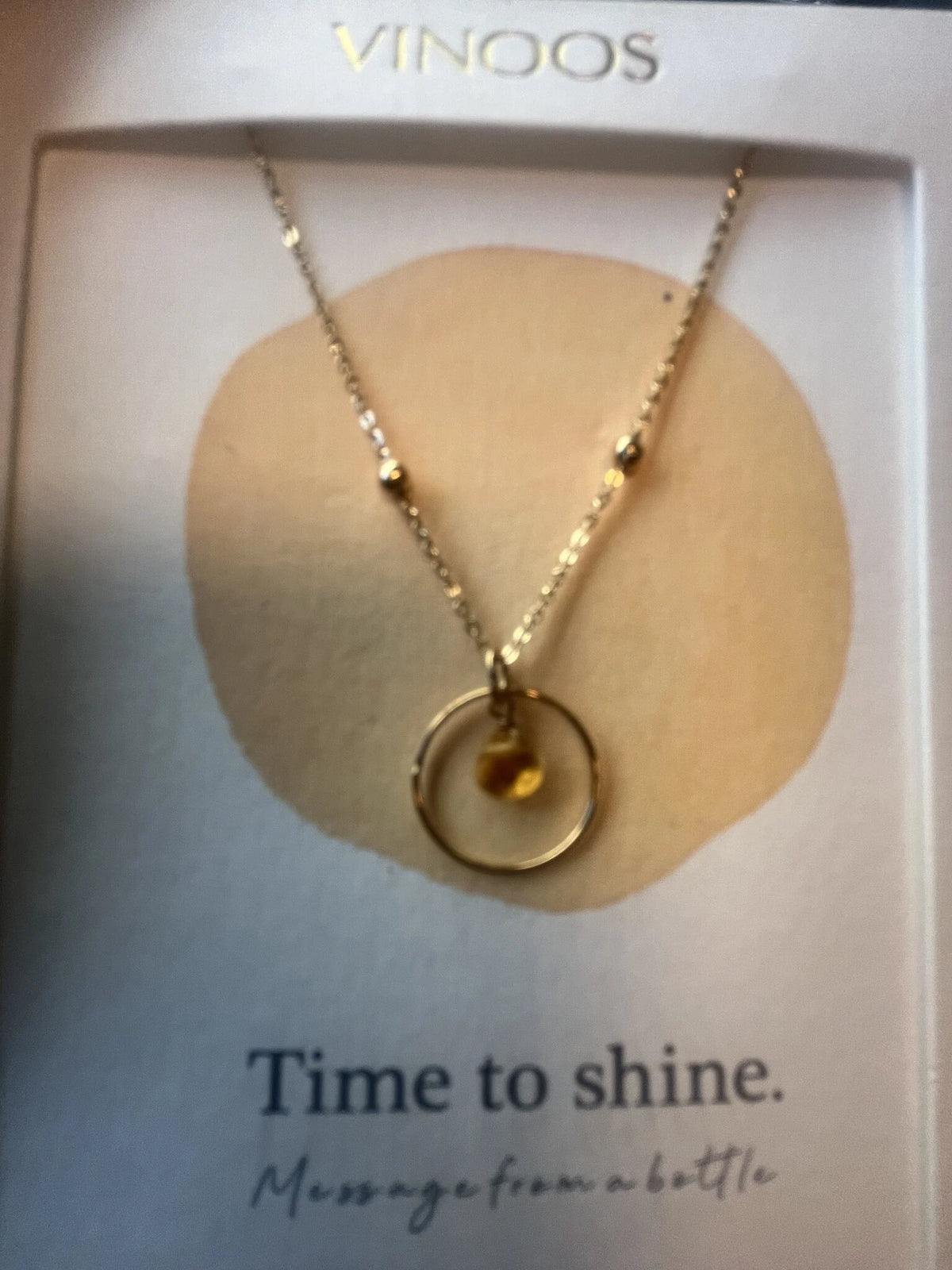 De goudkleurige Vinoos ketting Amber gepresenteerd op het bijbehorende quote-kaartje met de tekst Time To Shine